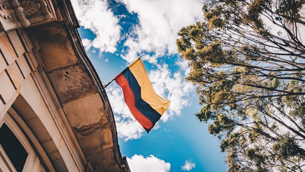 A Colombian flag atop a building from below