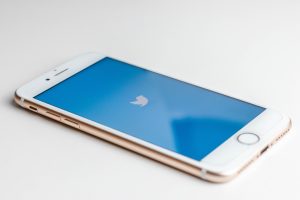 A photo of an iPhone on a white background with the twitter logo on the screen.