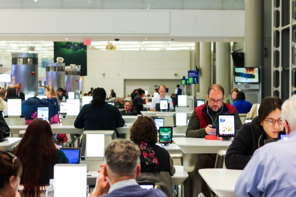A group of people sitting at tables looking at computers and tablets