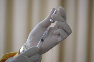 Gloved hands preparing a vaccine