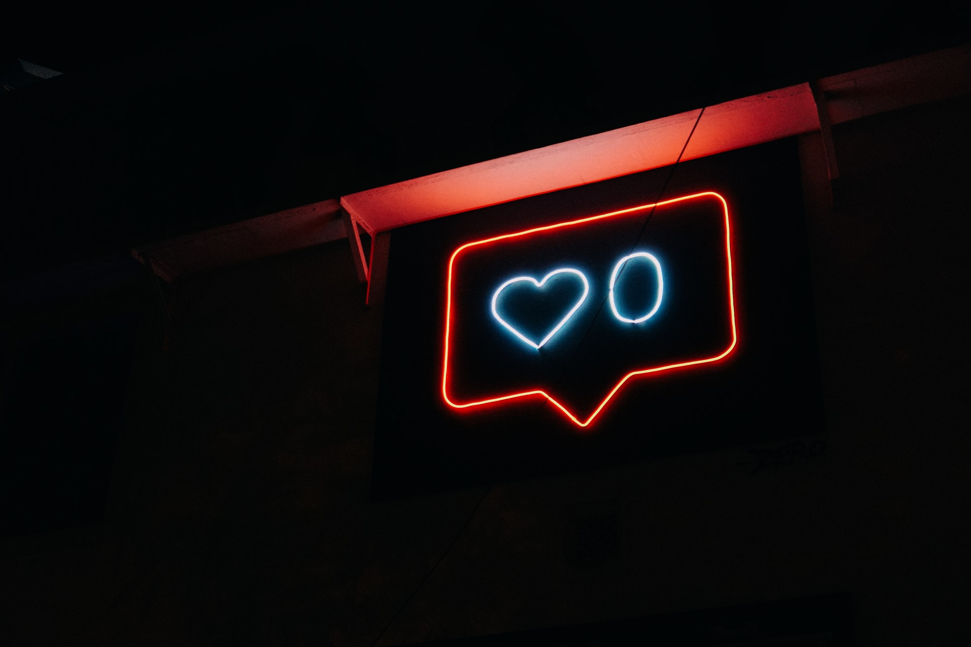 A neon sign in the shape of a speech bubble with a heart and the number 0 inside of it.