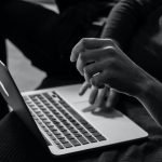 A black and white photo of someone using a laptop