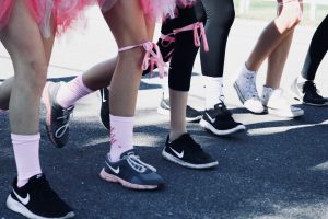 Several people's legs with pink decorations participating in a breast cancer walk
