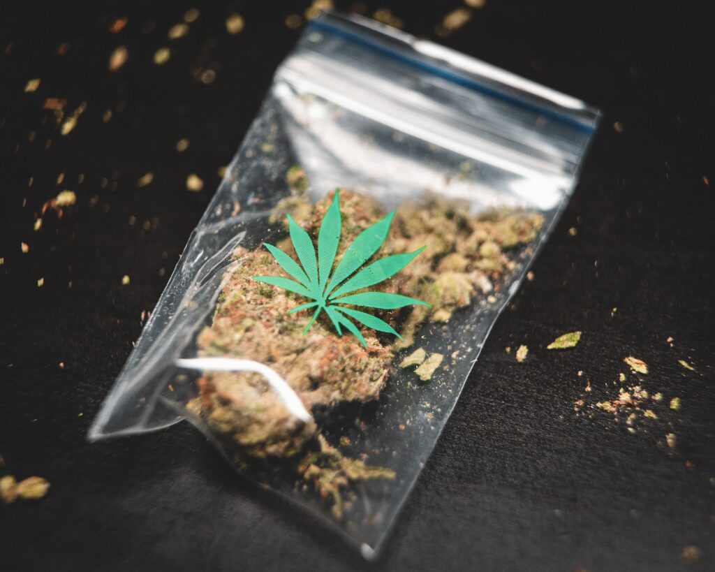A small clear plastic bag of marijuana with a green marijuana leaf icon printed on it.