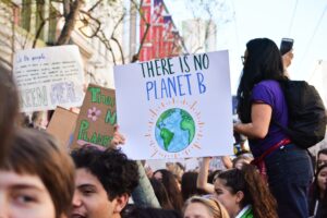 A group of people at a protest with a sign that says "There is no Planet B" with a drawing of the Earth.